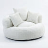Fauteuil rond en tissu blanc cassé avec dossier haut et deux coussins assortis.