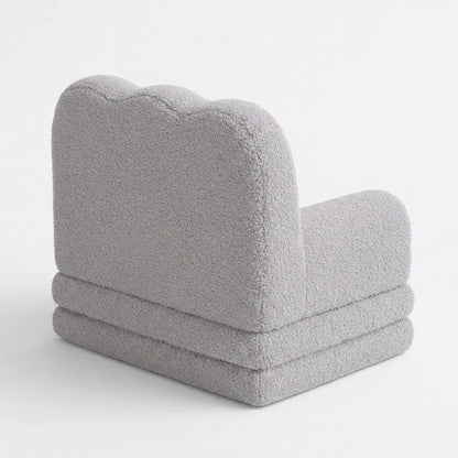 Fauteuil enfant gris moelleux, vue de côté, assise rembourrée et dossier arrondi texturé