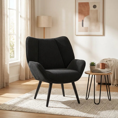 Fauteuil mid-century noir en velours côtelé, dossier capitonné et pieds fuselés.