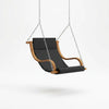 Fauteuil suspendu à assise rembourrée noire, structure en bois courbé et chaînes.