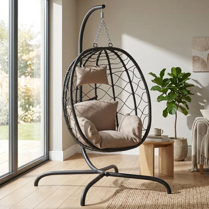 Fauteuil suspendu en rotin noir avec coussins beige, coque ovale et base métallique.