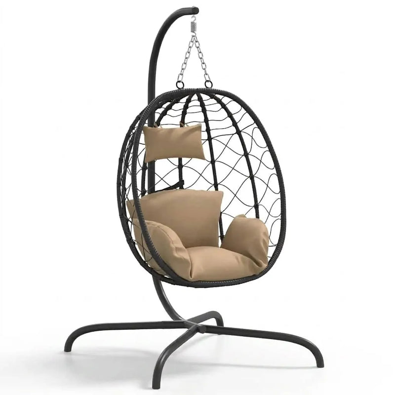 Fauteuil suspendu en rotin noir, coussins beige et structure ovale sur piètement courbé.