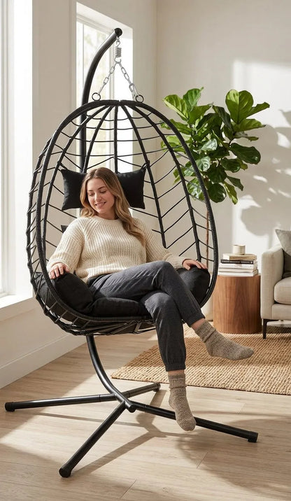 Fauteuil suspendu noir en treillis métallique, coussins épais, personne assise