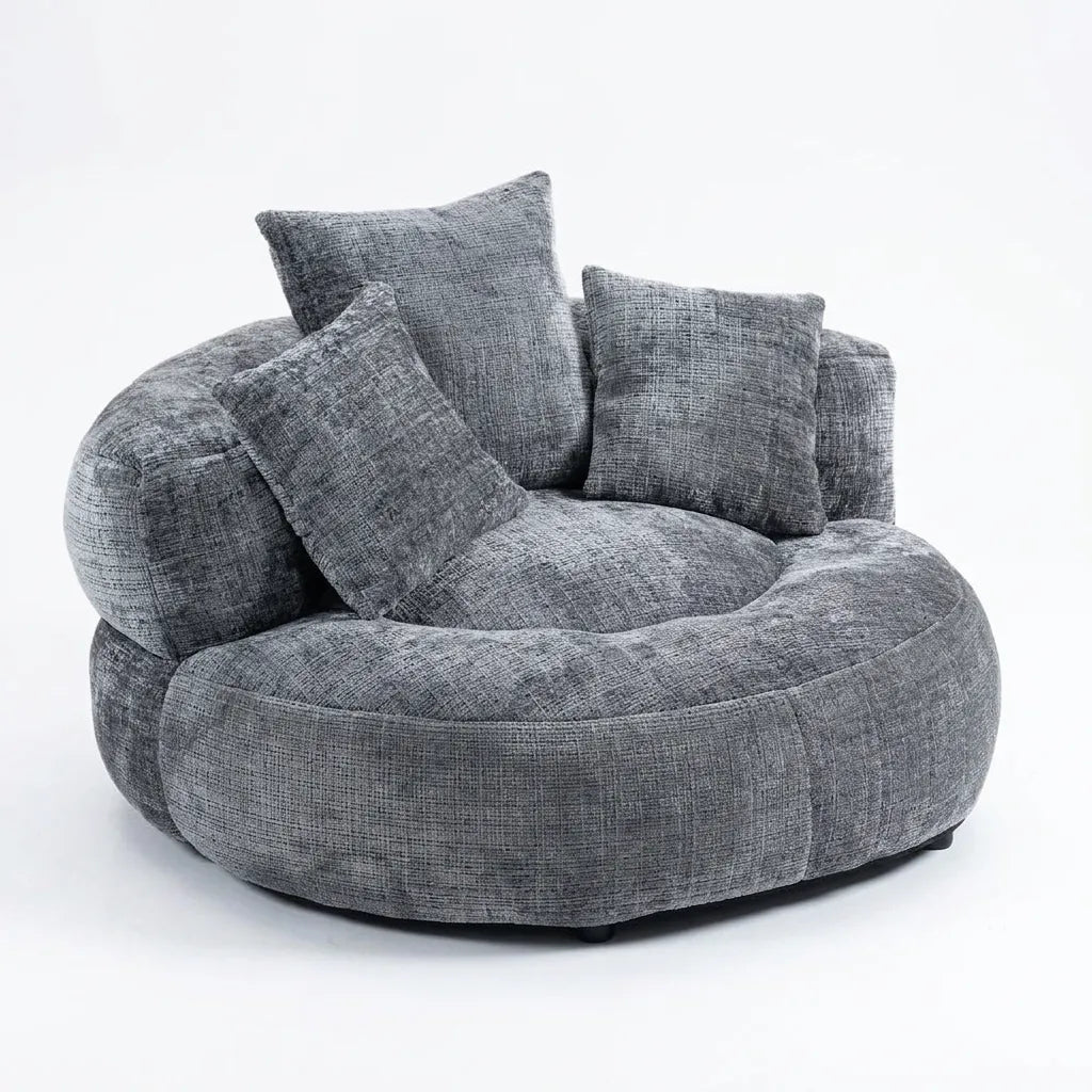 Fauteuil rond en tissu gris avec dossier haut et trois coussins décoratifs.