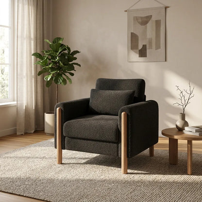Fauteuil rembourré en tissu foncé, dossier haut et pieds en bois clairs